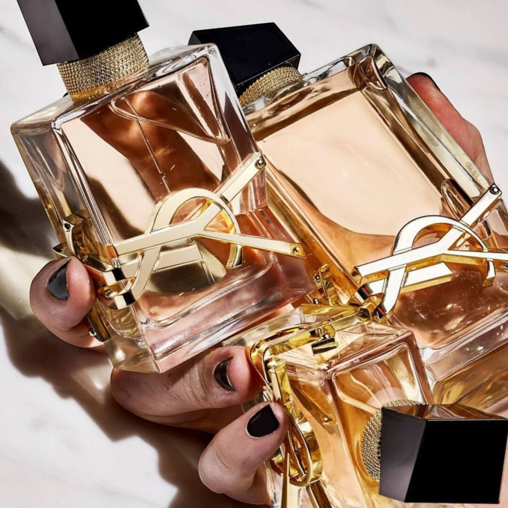Frascos de perfume Yves Saint Laurent Libre de Distriwil con logo dorado y diseño elegante en manos