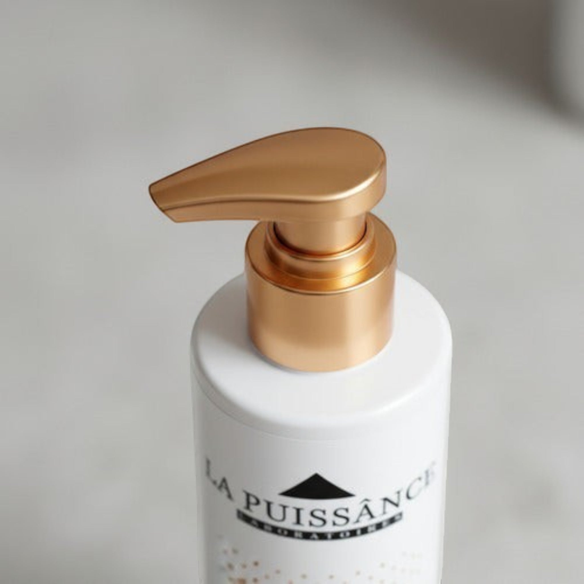Detalle de envase blanco con dosificador dorado de Distriwil, parte del kit de tratamiento capilar La Puissance.