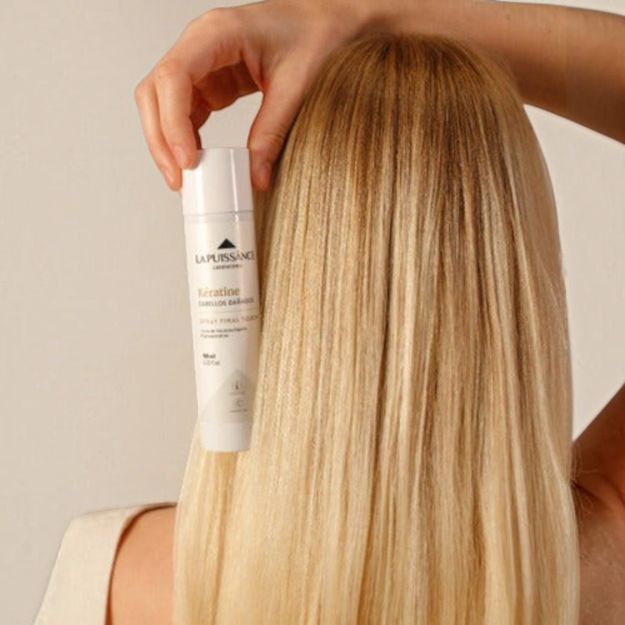 Mujer rubia sosteniendo el spray reparador de keratina Distriwil La Puissance para cabello dañado